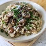 Mushroom risotto topped with mushrooms, parsley, and grated cheese.