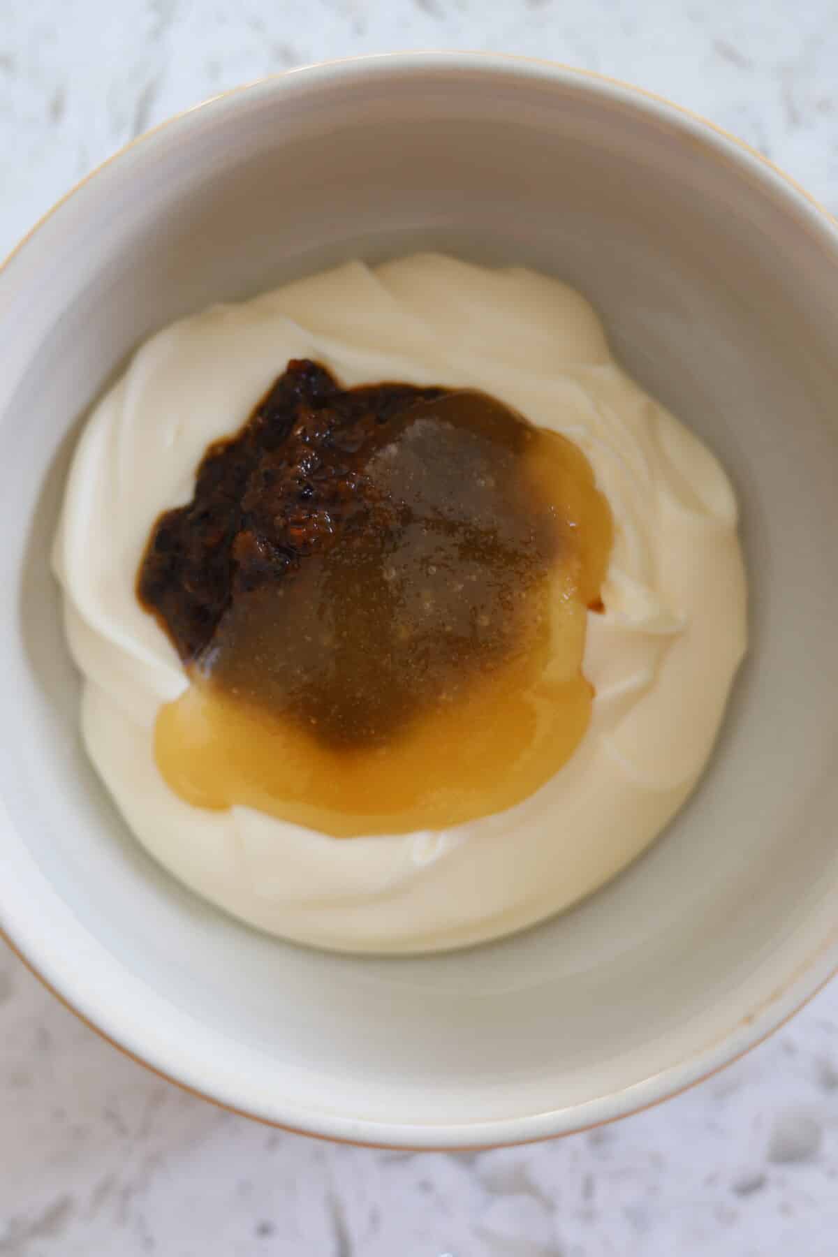 Bowl of mayonnaise with jerk marinade and honey on top.