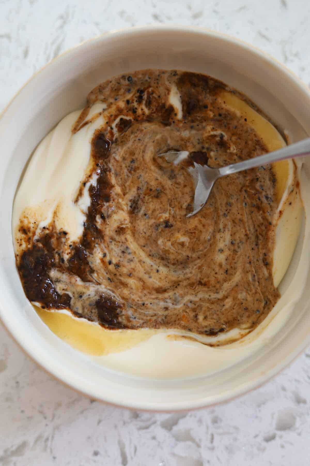 Spoon swirling jerk marinade, honey, and mayonnaise mixture.