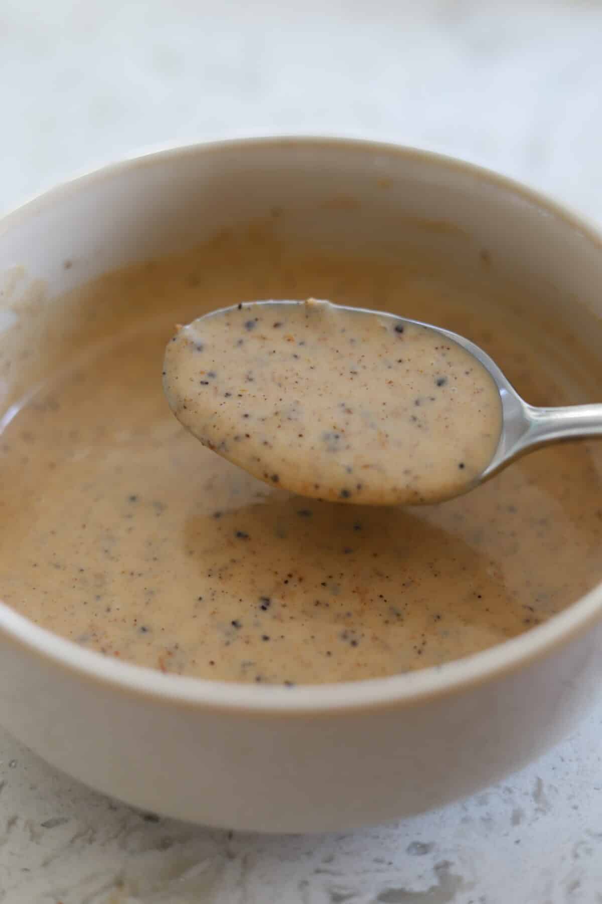 Spoon hovering over bowl of smooth jerk sauce.