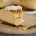 Close-up of cheesecake slice with whipped cream and nutmeg dusting.