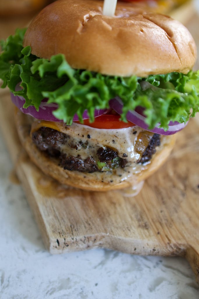 Jerk burger with lettuce, tomato, onion, and honey jerk mayo on a bun.