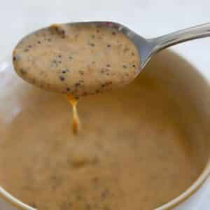 Spoon lifting creamy jerk sauce from a small bowl.