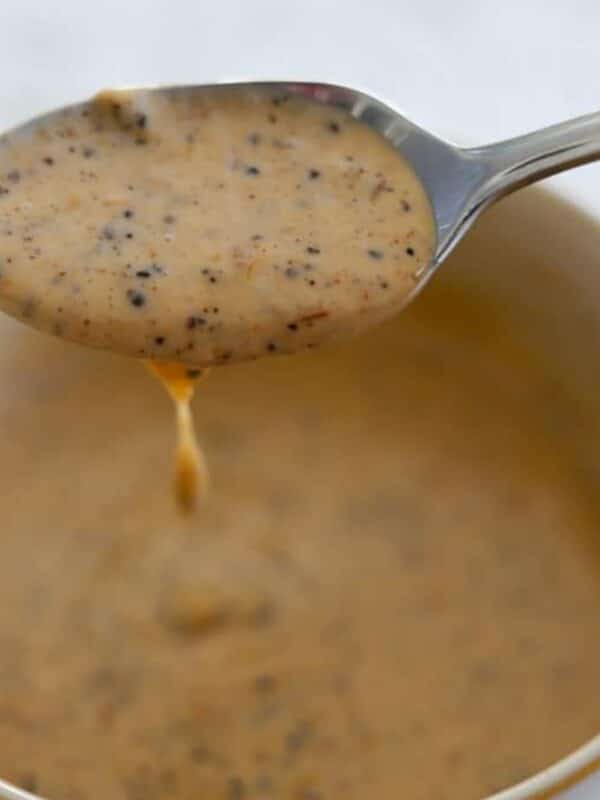 Spoon lifting creamy jerk sauce from a small bowl.