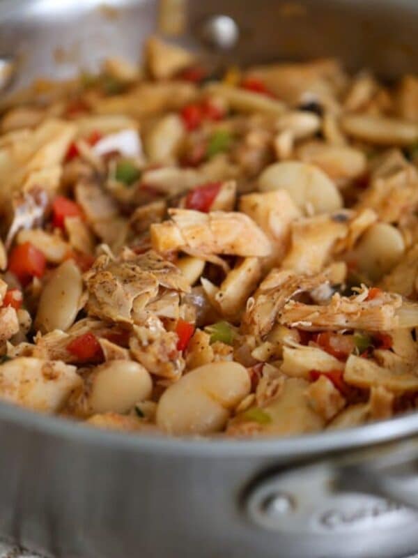 Finished saltfish and butter beans dish in a skillet, showing tender fish and beans coated in sauce.