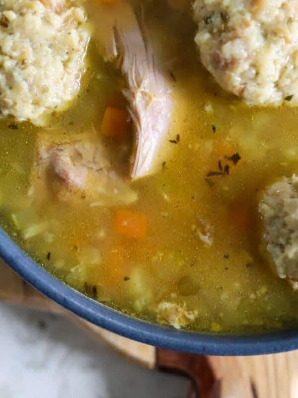 Turkey soup simmering with dumplings and black pepper on top.
