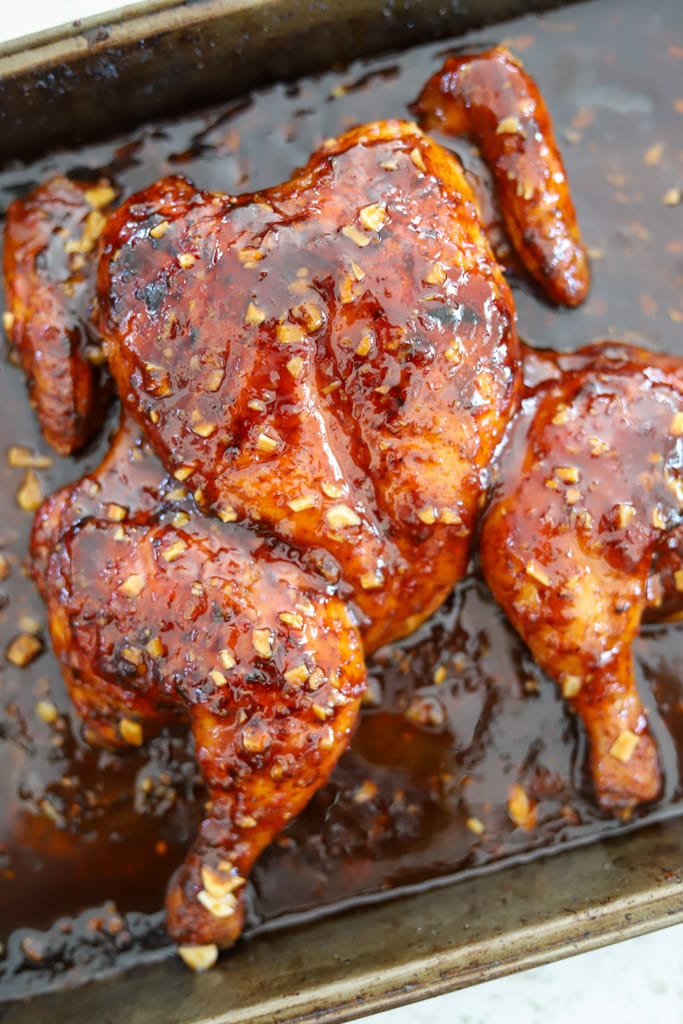Spatchcock chicken glistening with a thick layer of sweet chili glaze.