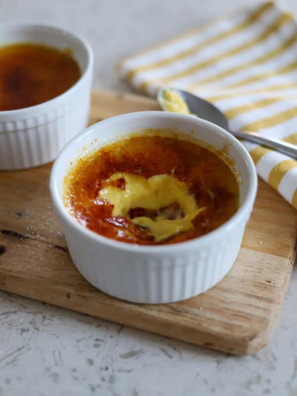 Eggnog crème brûlée with caramelized sugar topping and sprinkled nutmeg served in white ramekin.