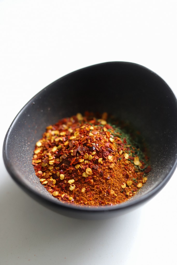 Homemade Jamaican jerk seasoning dry rub in a dark bowl with red chili flakes