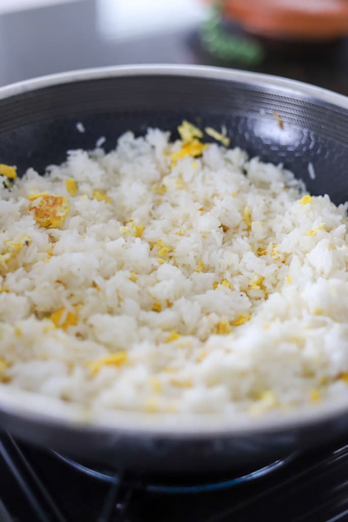 Scrambled eggs mixed into rice in a wok.