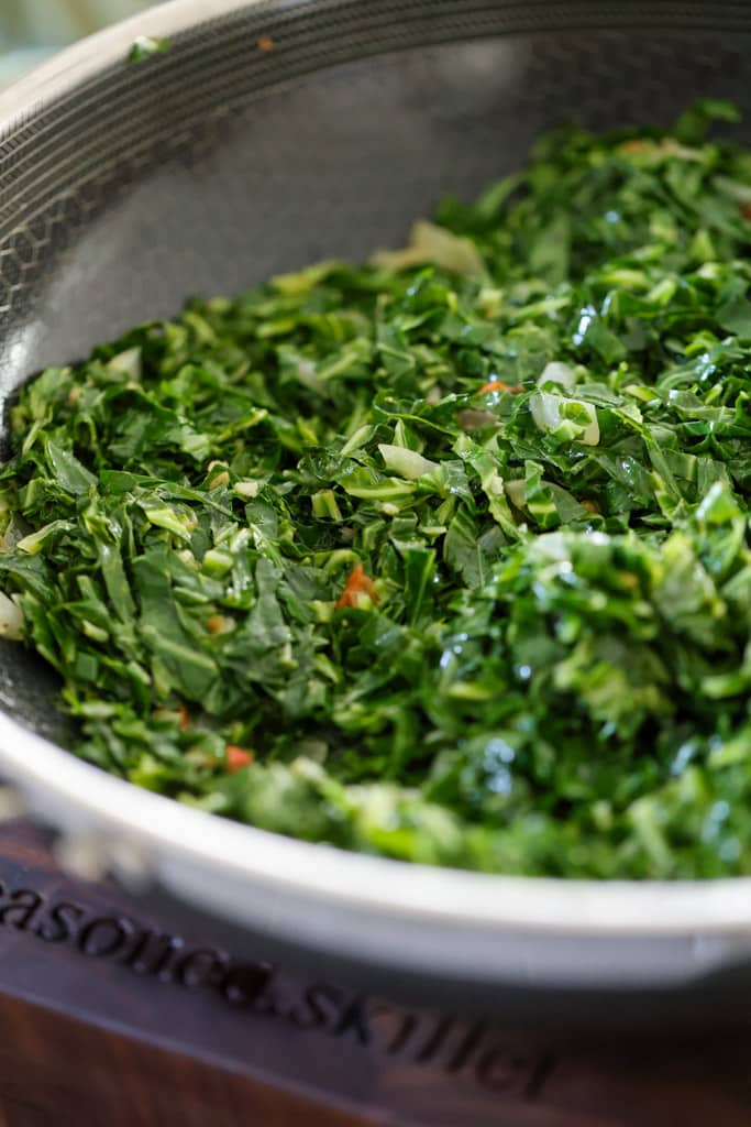 saut&eacute;ed collard greens in seasoned skillet pan.