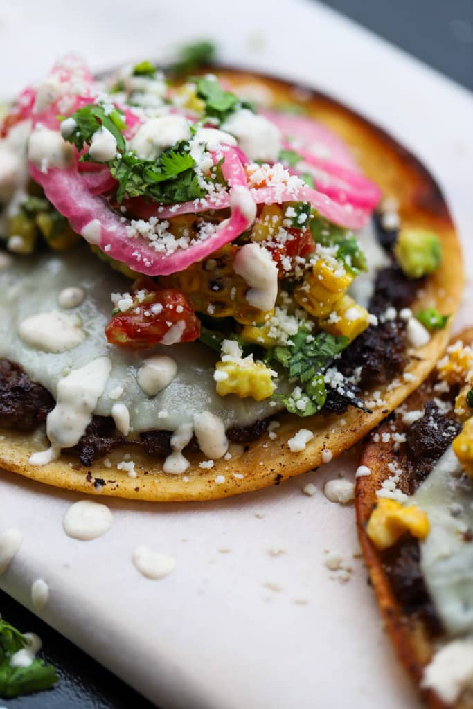 Final plated jerk smash burger tacos garnished with fresh toppings.